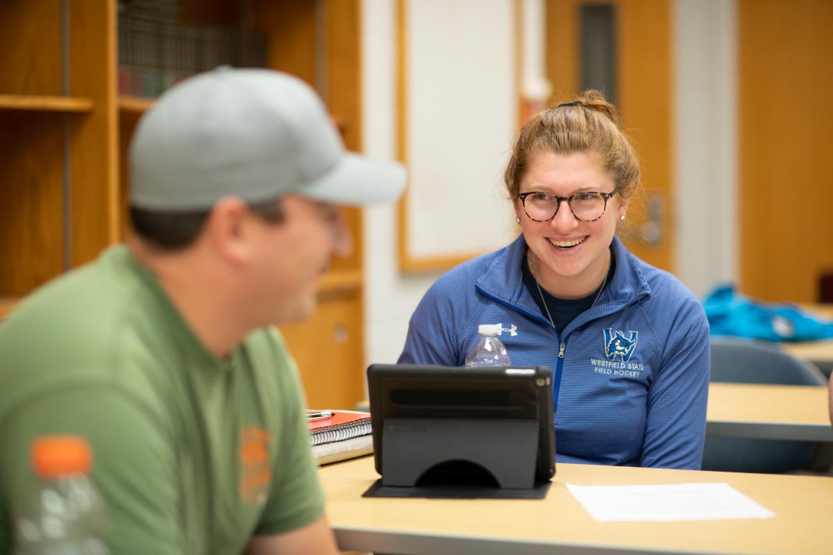 Student smiling with laptop in Public Administration course