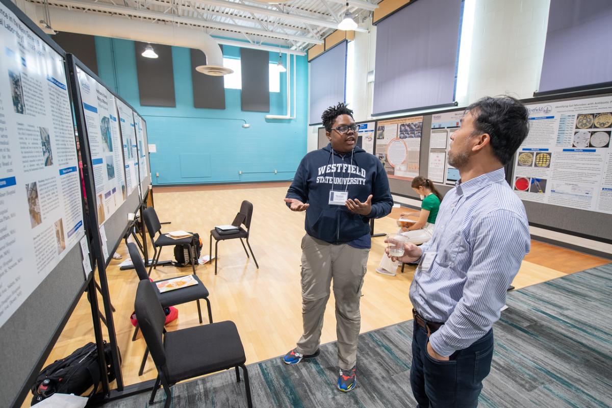 CURCA Celebration featuring a student wearing navy WSU sweatshirt presenting their research to a biology faculty member.