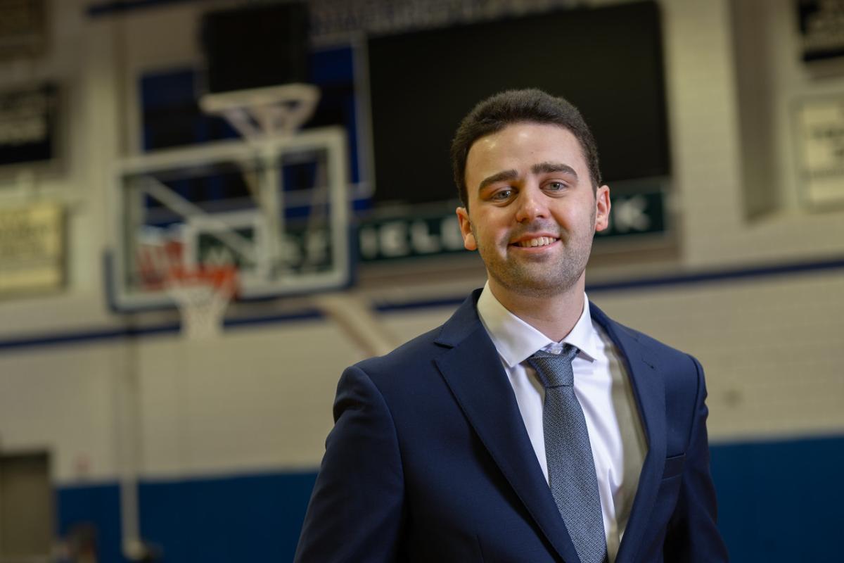 Sports management student smiling during an internship on a basketball court.