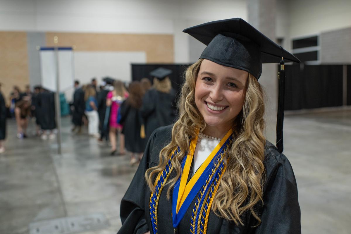 Criminal Justice 4+1 student smiling wearing a cap and gown at commencement.