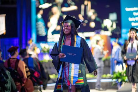 Graduate walks from stage holding diploma