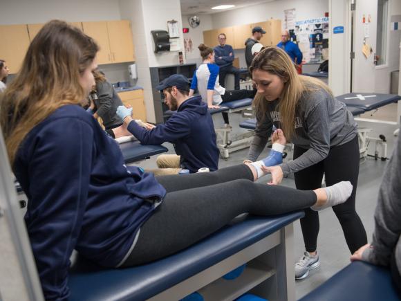 A Westfield State student aids with wrapping an ankle.