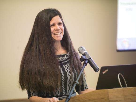 Dr. Catherine Savini stands at a podium and speaks into a microphone