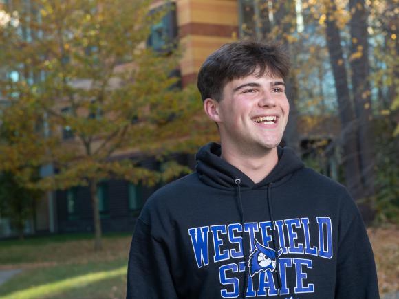 Psychology student wearing WSU sweatshirt smiling with fall leaves in the background.