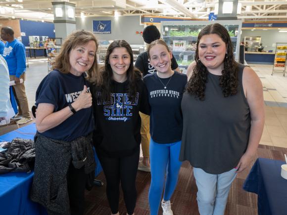 Education faculty member giving thumbs up smiling with three students.