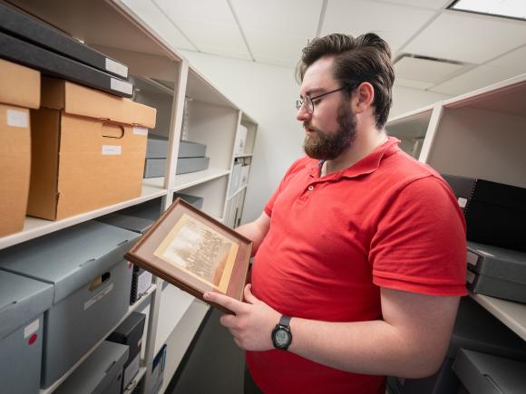 English student working on a historical project holding a black and white photograph.