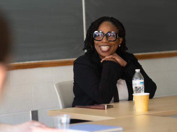 Woman smiles at table speaking to students