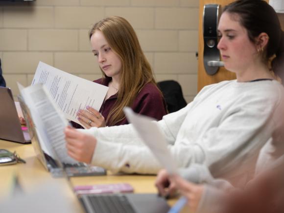 Two students in a Forensic Psychology class reviewing notes together during a lecture.