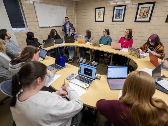Forensic Psychology class with students seated around a round table taking notes.