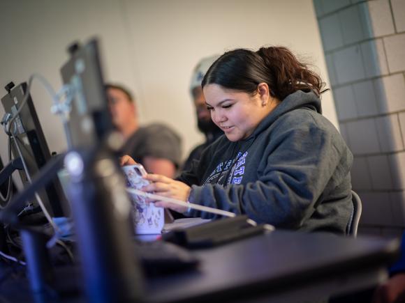 Management student focused on a classroom project while working at a computer.