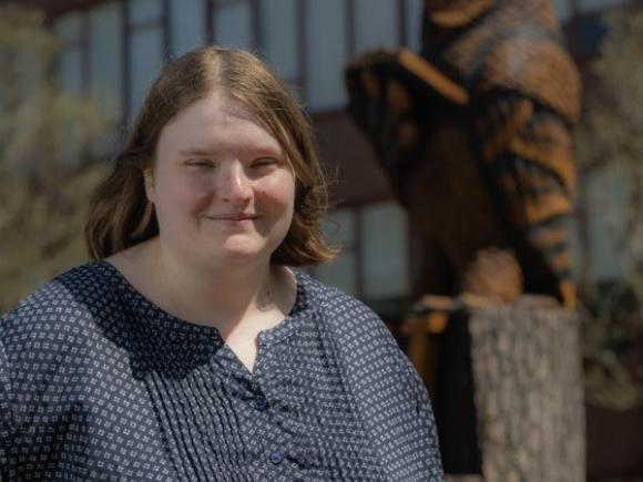 Melissa Costello smiling on campus in front of an owl statue.