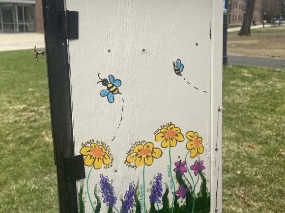 A campus board decorated with a garden scene of flowers and bees.