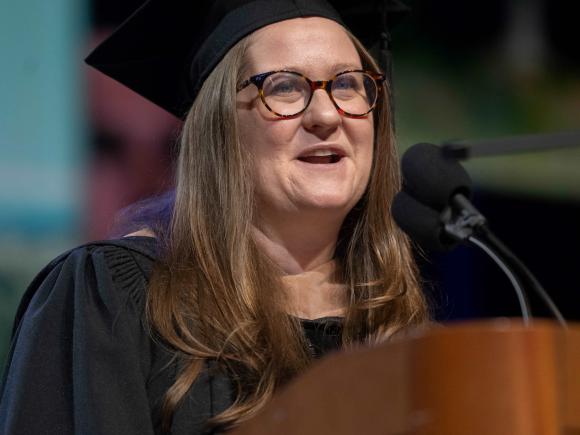 Woman speaking at podium in regalia Commencement 2025