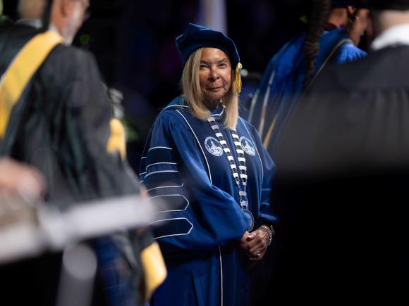 Woman in academic regalia looks at camera