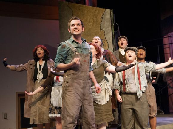 Students wearing customs acting in the production Urinetown.