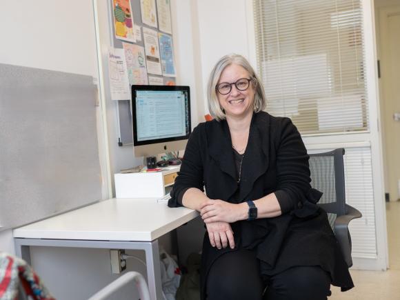 Student smiling while working at a desk with a computer.