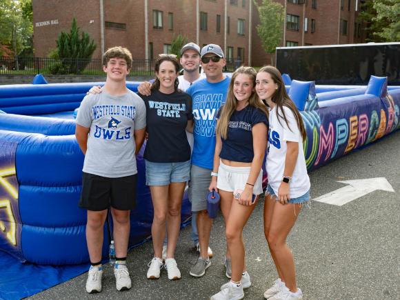 Family stands in front of inflatable game wearing Westfield State tshirts