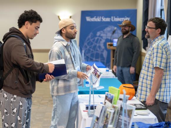 Students talk to professors at a table