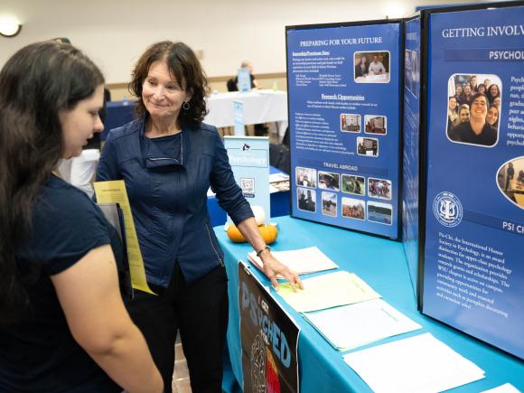 Student and Faculty member look at poster about Psychology program