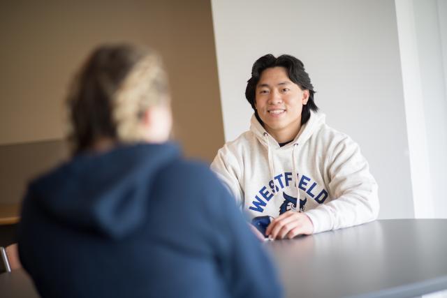Male student smiling as he talks to a friend in the Ely Campus Center