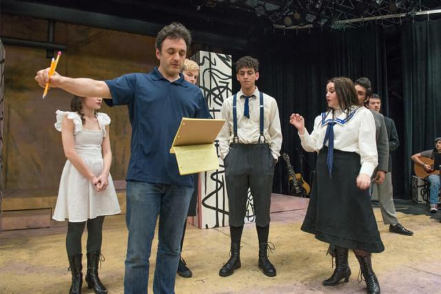 Multiple students dressed in costume take stage direction from Theater Arts Professor Eric Parness.