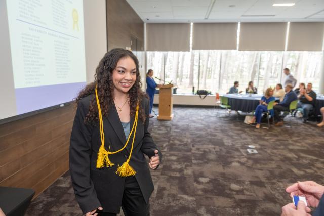 Student at the Honors Symposium event with yellow honors cord around her neck.
