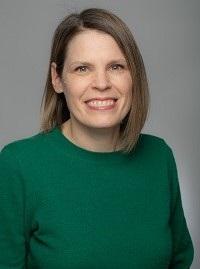 Celeste wearing green shirt with brown shoulder length hair smiling.