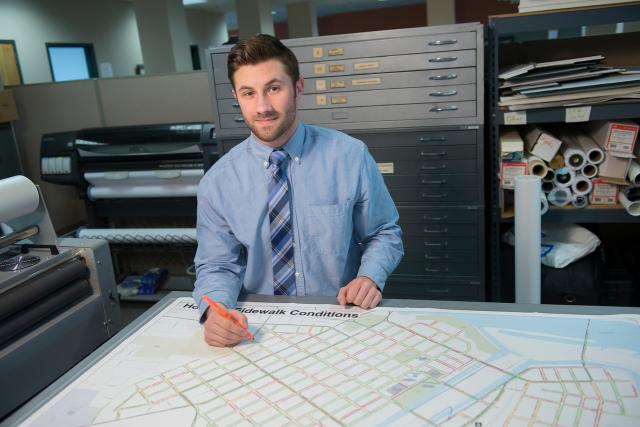 Student intern sitting at a desk looking at building plans.