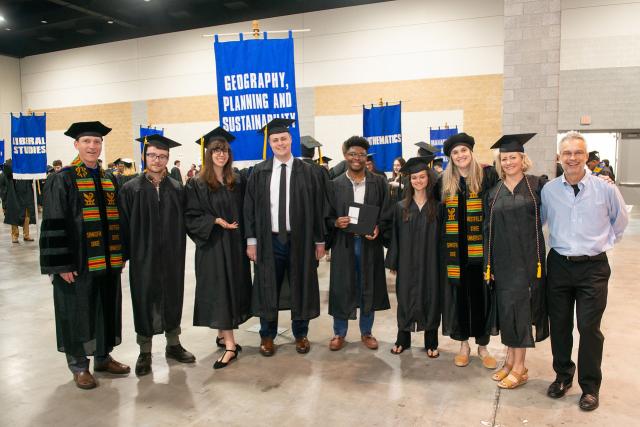 GPS students and faculty members smiling at commencement ceremony.