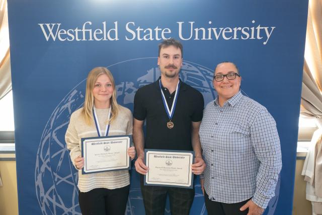 Movement Science students smiling with a faculty member at an academic awards ceremony.