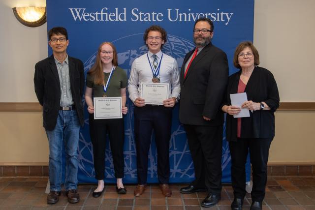 Political science students smiling with faculty at an academic awards ceremony.