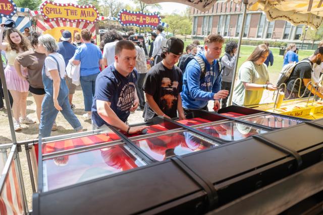 Three students playing games at a spring carnival on campus.