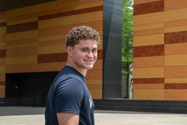 Student smiling sitting outside of University Hall.