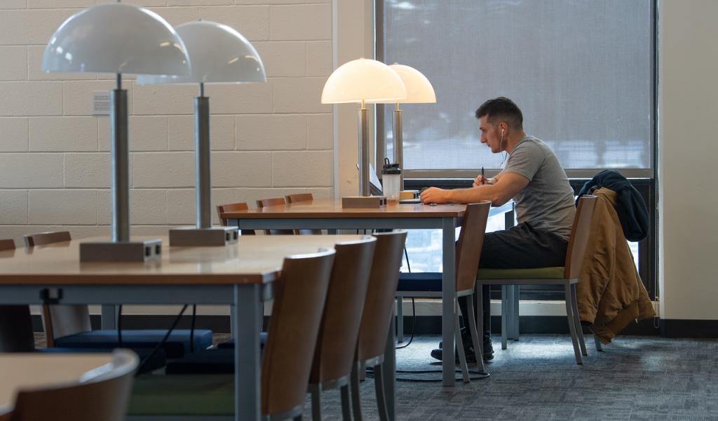 Student studying in Ely wearing grey shirt and black pants with headphones on.