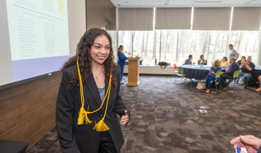 Student at the Honors Symposium event with yellow honors cord around her neck.