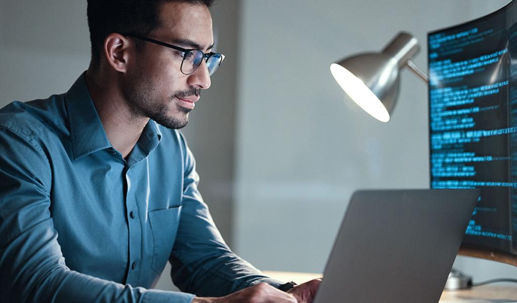 Cyber Security guy sitting on laptop with lamp