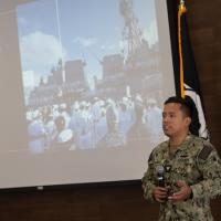 Josue “Alex” Ramos, Navy veteran and former Veterans Affairs work-study student at Holyoke Community College, speaking at Veterans Day at Westfield State. A projector behind him is showing a photo from Pearl Harbor, 2015.