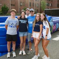 Family stands in front of inflatable game wearing Westfield State tshirts